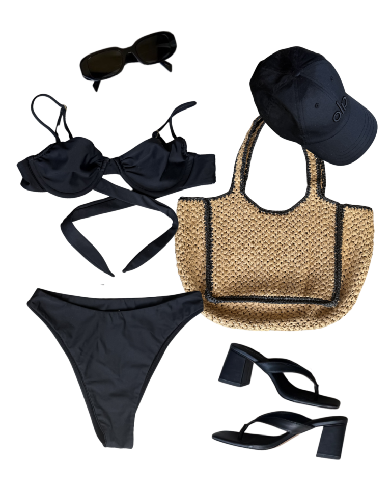 Flat lay image of black bikini and accessories (Alo hat, black sunglasses, crochet beach bag, sandal heels)